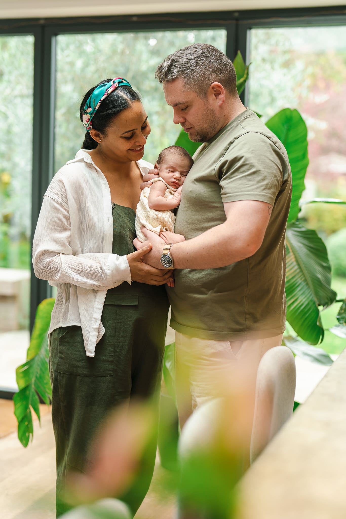 Parents holding their newborn baby during an at-home newborn photoshoot in Surrey.