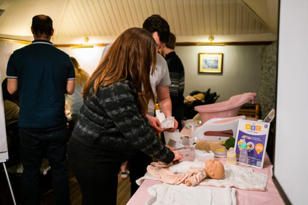 New parents practicing changing a diaper during an antenatal class in Caterham